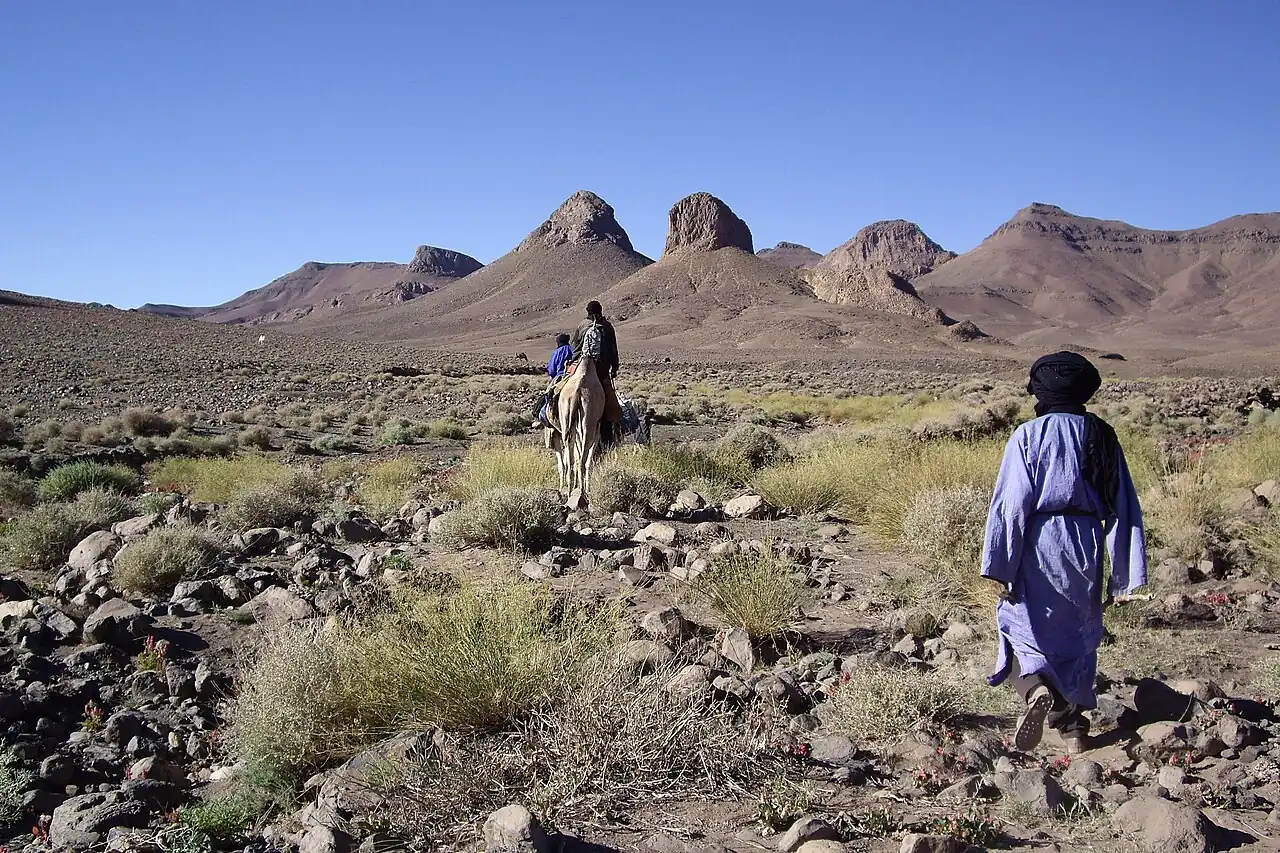A robed figure walking through a rocky desert valley