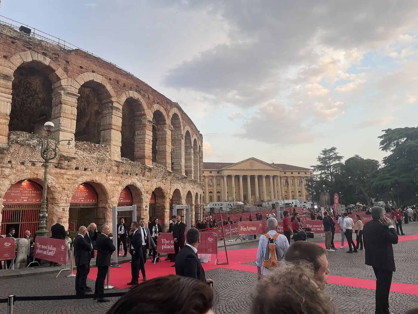The arched wall of the Arena with a red carpet and crowd