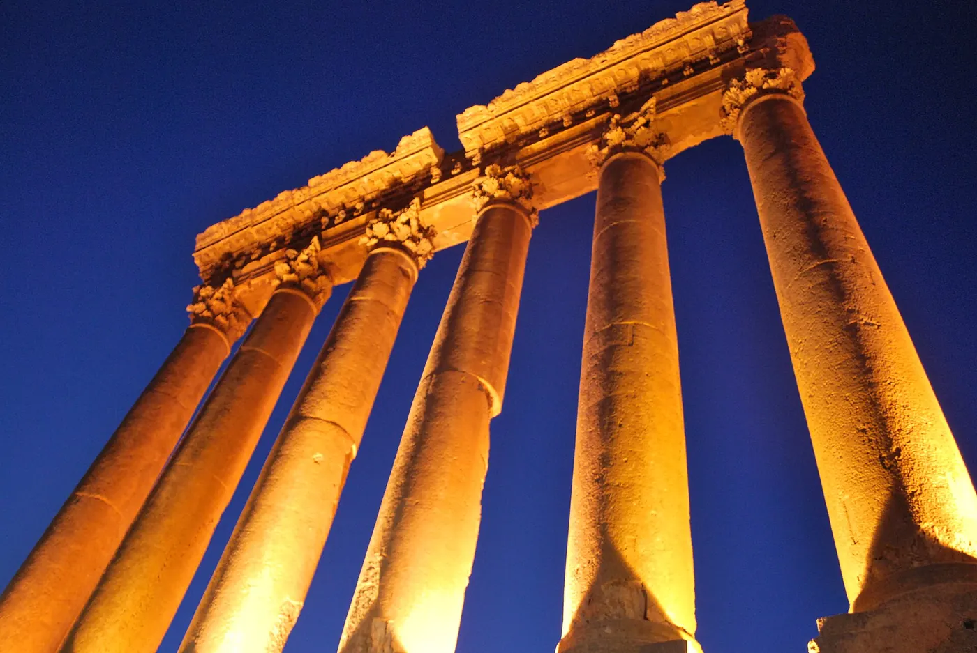 Floodlit columns of the Temple of Jupiter against a blue sky