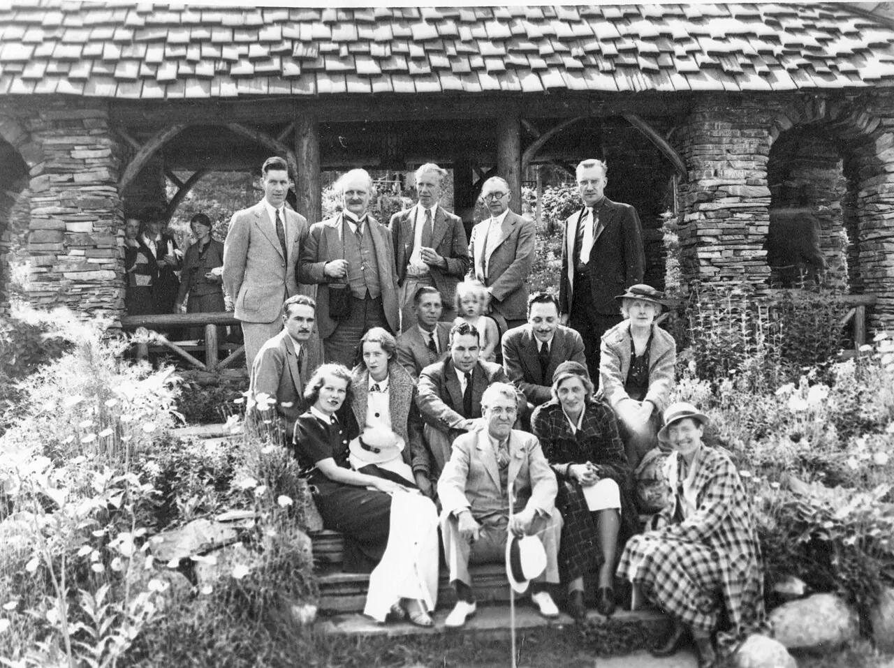 A black-and-white photograph of a group gathered outside a stone building