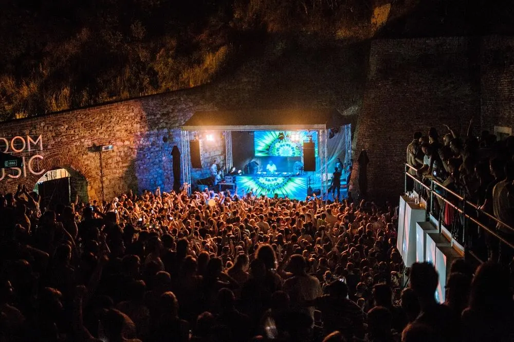 A crowd and stage in a stone-walled space at night