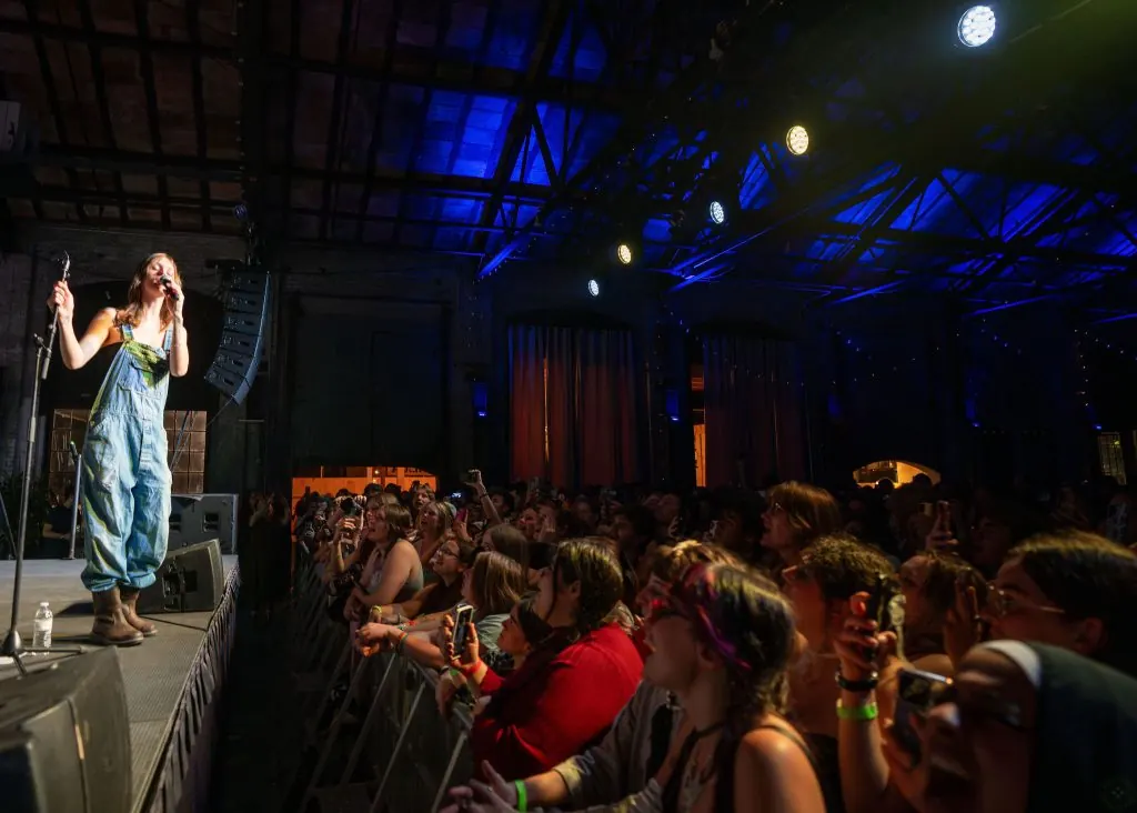 A singer performing on a lit stage in front of a seated crowd