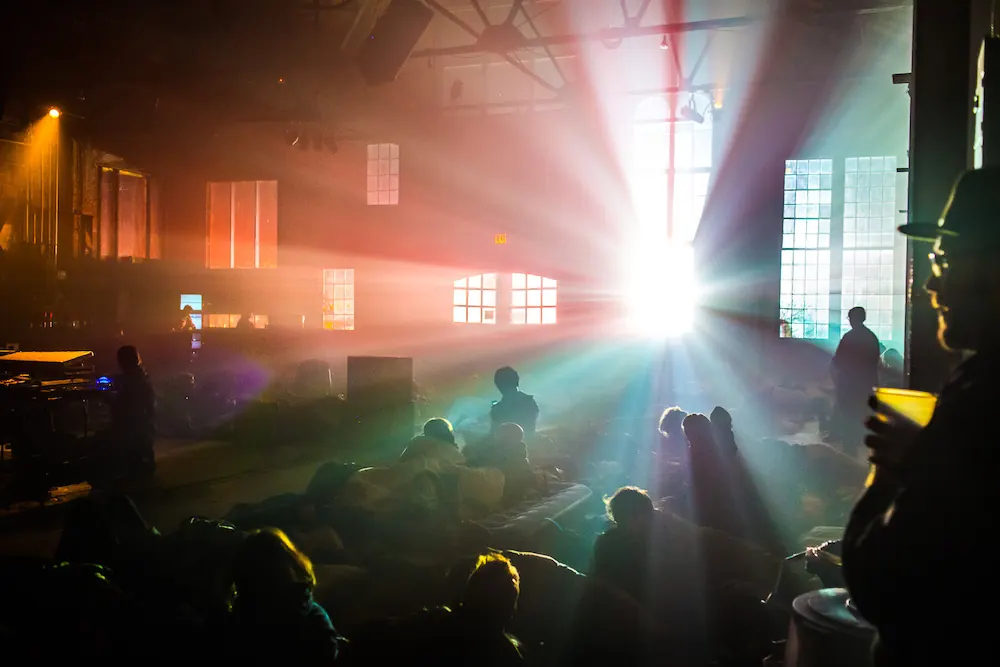 A bright shaft of light across a dark, hazy warehouse space