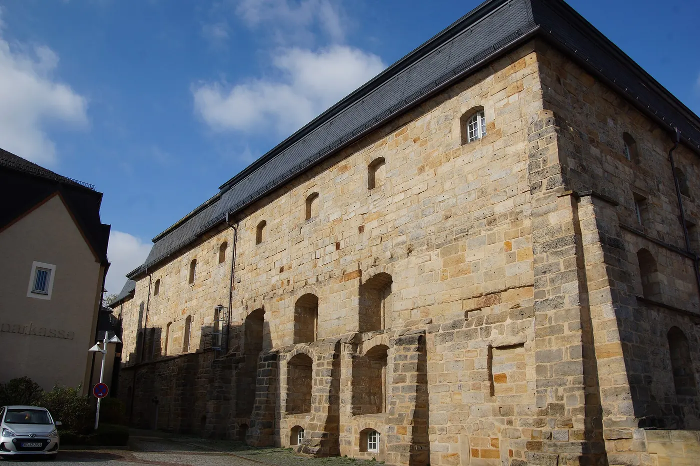 The dark-roofed stone side wall of the opera house against a blue sky