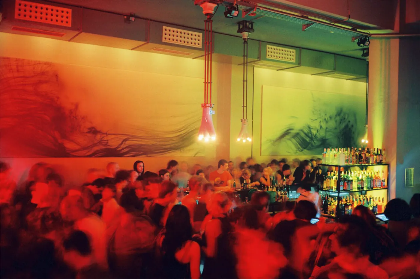 A blurred, colour-streaked crowd inside the hall, in red and orange light