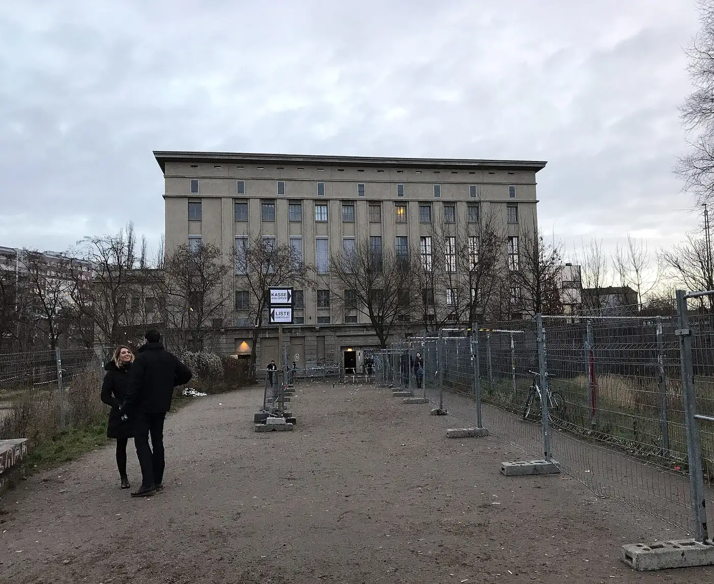 The Berghain building seen across a bare courtyard, with a person walking