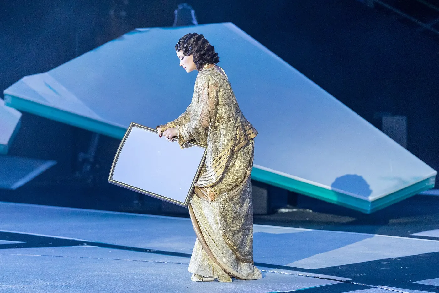 A soprano in a gold gown on a blue platform