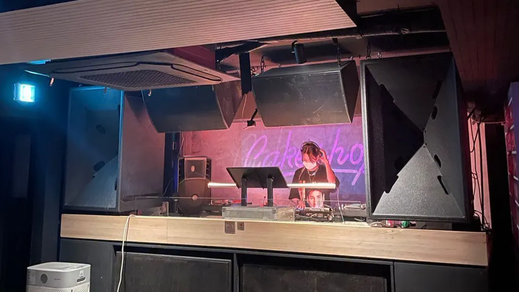 A DJ working at a booth in a glass-fronted room