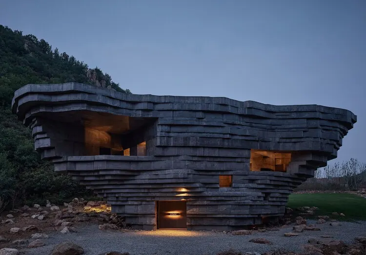 The layered concrete exterior of the chapel among trees