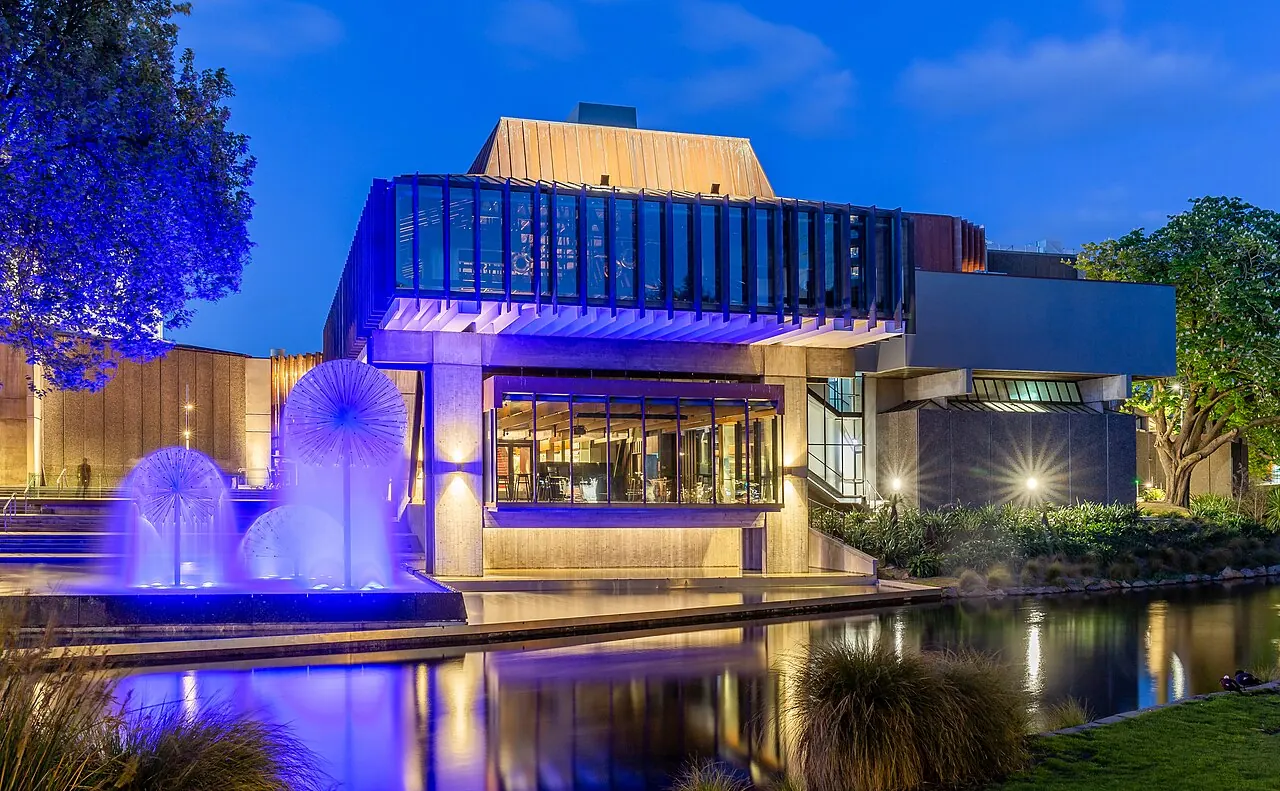 The town hall reflected in a pool, lit blue and purple