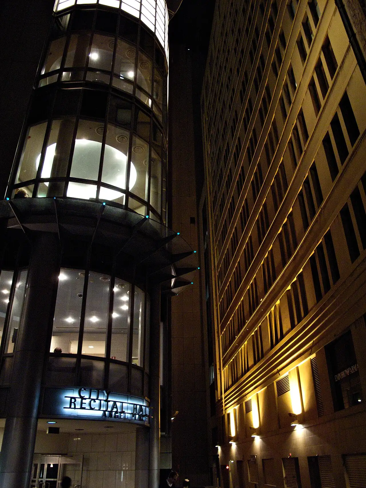 A glass-fronted tower at night in Angel Place