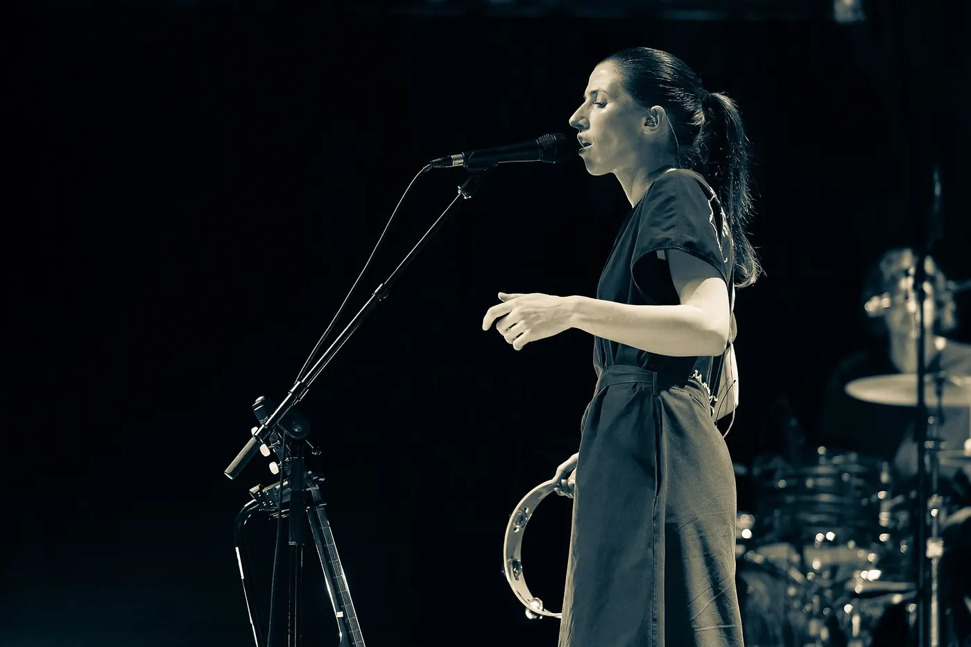 A singer standing at a microphone on the dark stage