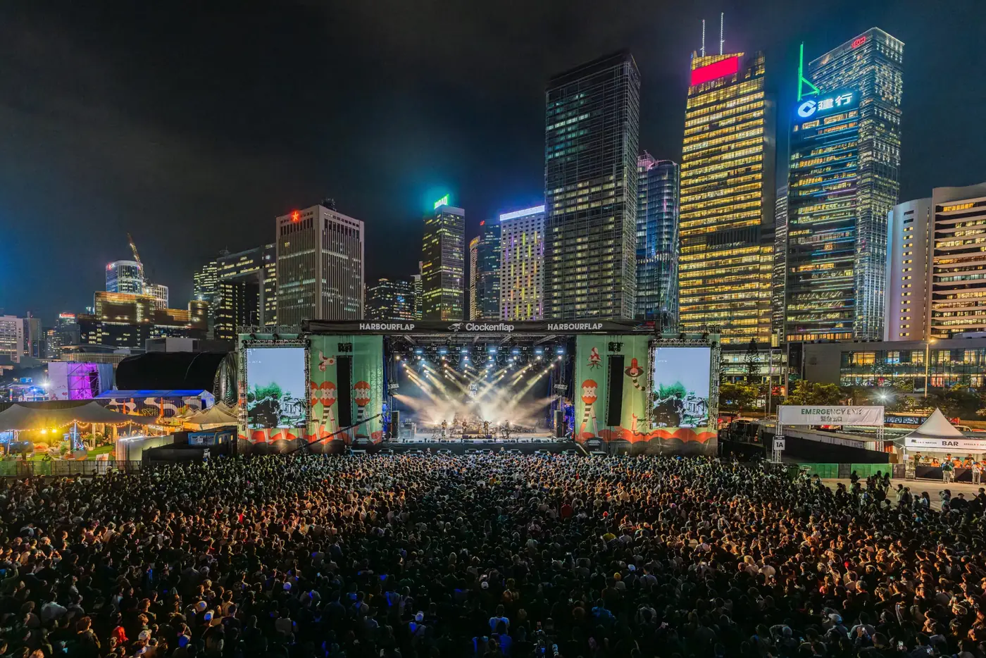 The festival crowd and stage below lit skyscrapers