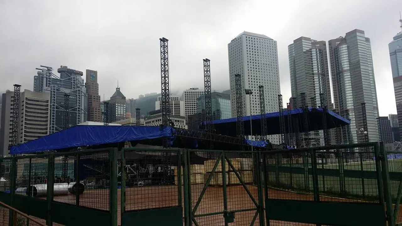 A festival stage with a blue canopy in front of tall buildings