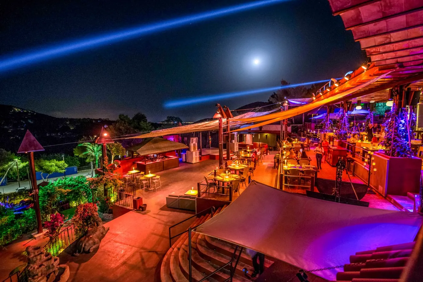 The Cova Santa terrace at night, with a blue light beam across the sky