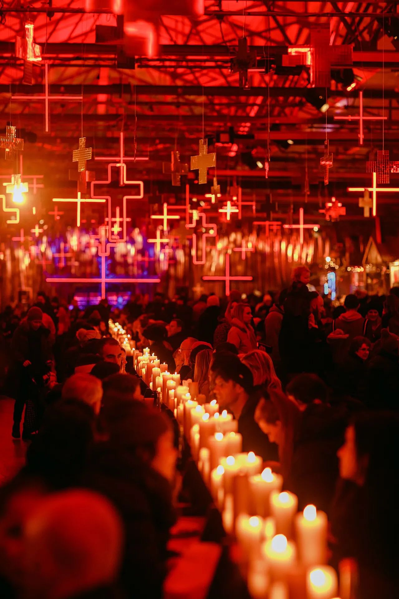 A red-lit hall with candles and long tables