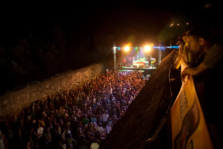 A crowd at night facing a stage beside a fortress wall at Fort Punta Christo, from the Pula years