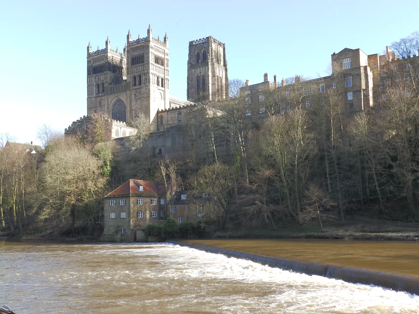 Durham Cathedral's western towers above the River Wear, the Old Fulling Mill and the weir in winter sun