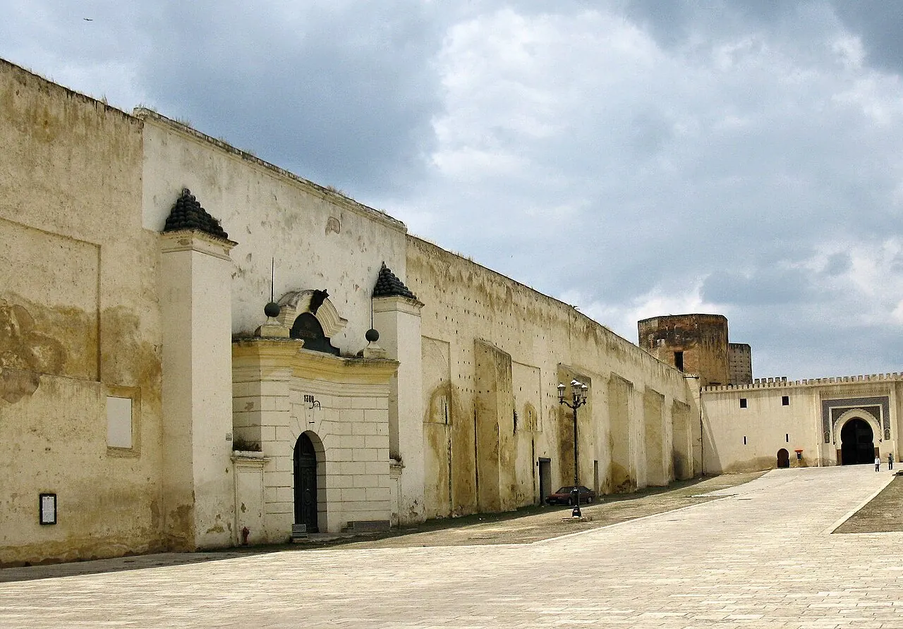 A long sand-coloured city wall along an empty street