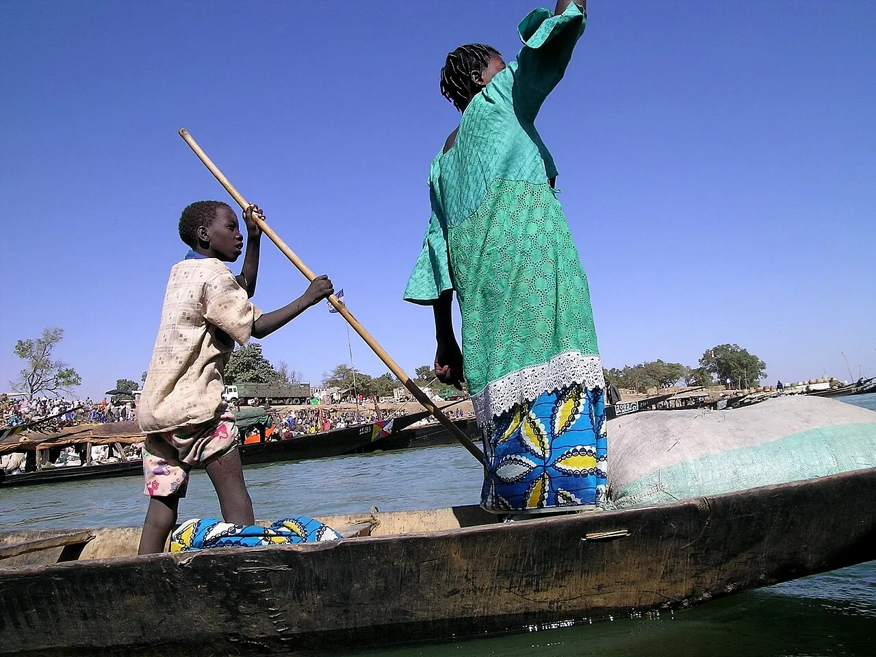 Two people in a pirogue on the Niger, one poling