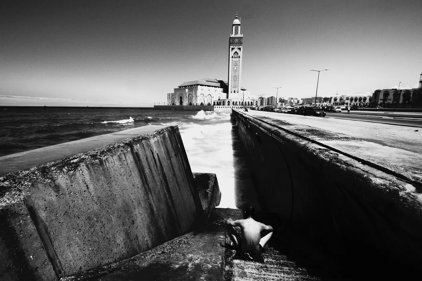 A black-and-white view of the sea wall with the minaret in the distance