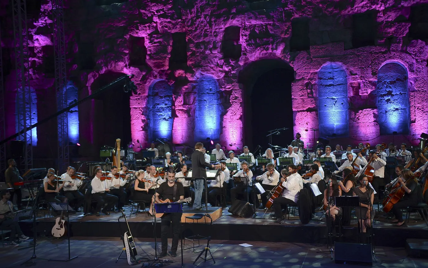 An orchestra playing in the lit Odeon at night