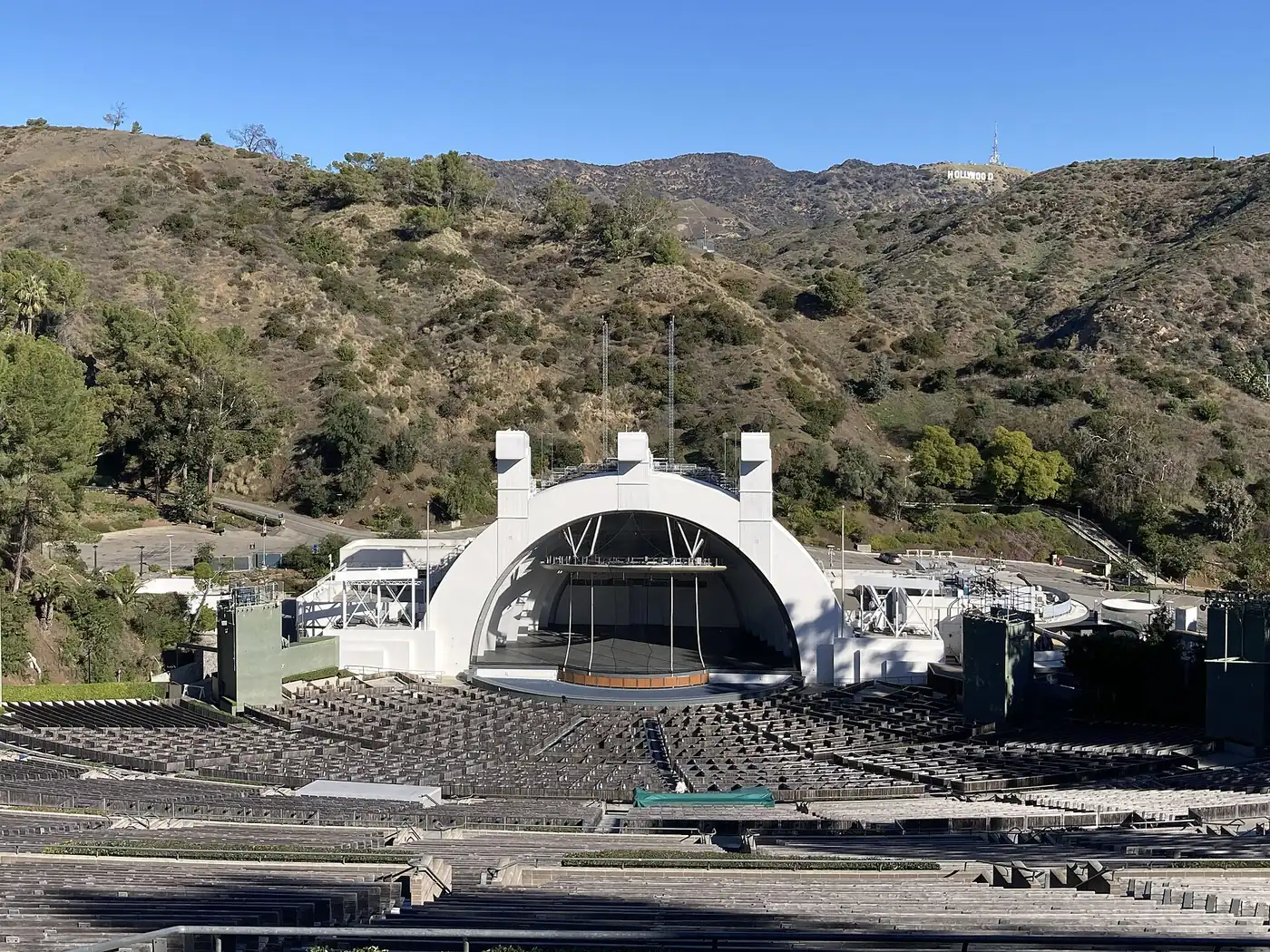 The empty Hollywood Bowl seen from the upper benches, its white shell in the canyon with the Hollywood sign on the hills beyond