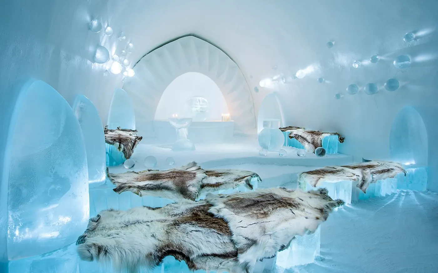 A carved ice suite with reindeer furs on ice blocks at the Icehotel