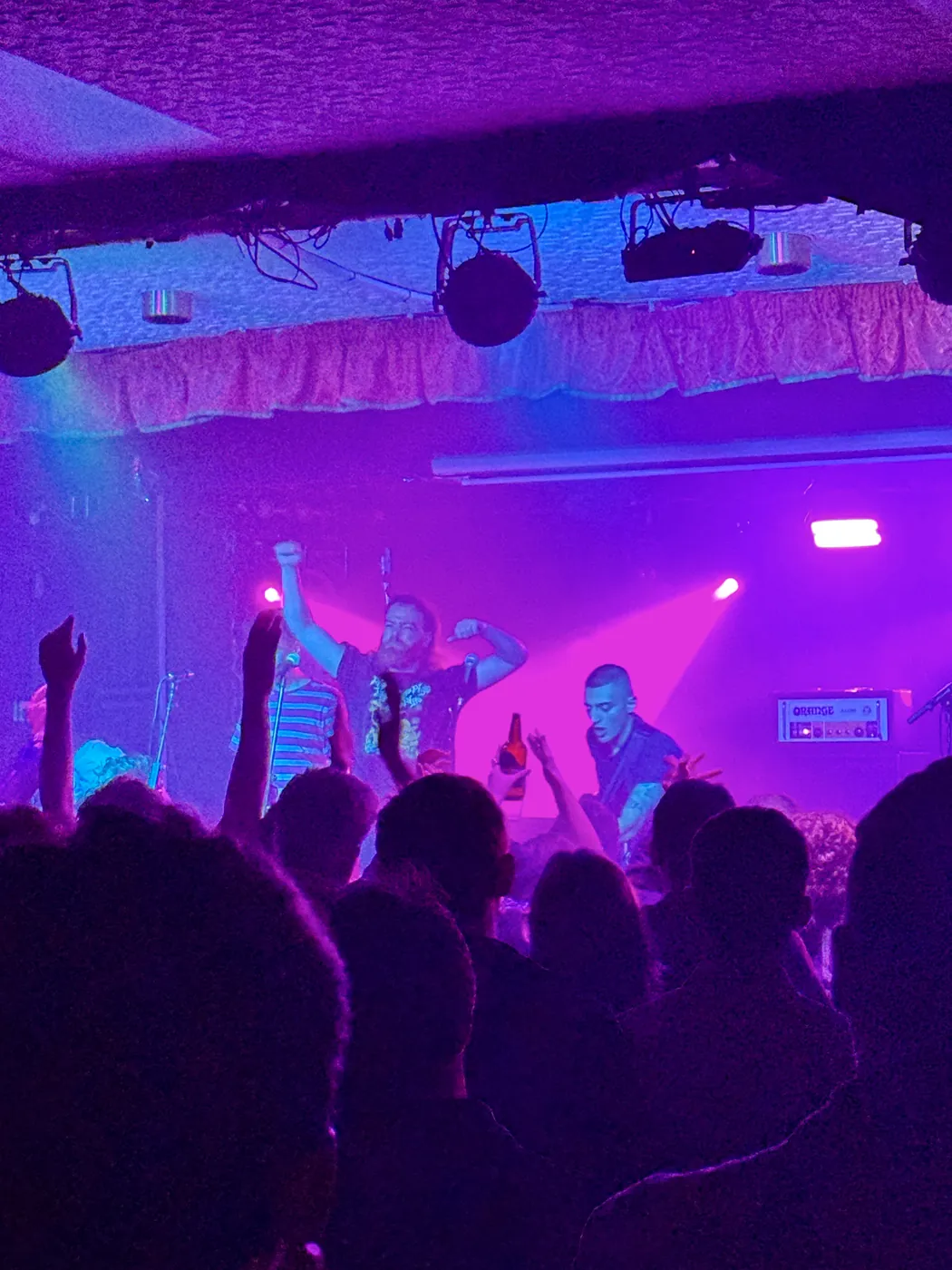 Knats on stage in the upstairs concert room under magenta and blue light, arms raised in the crowd, 23 October 2026