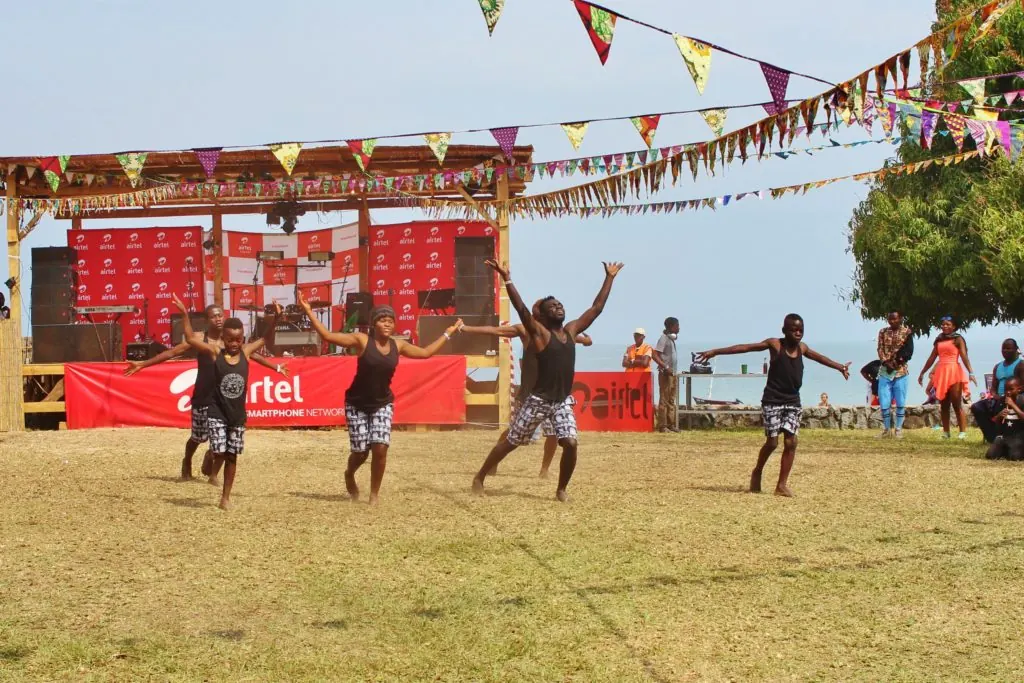 Dancers performing on grass in front of a red festival banner