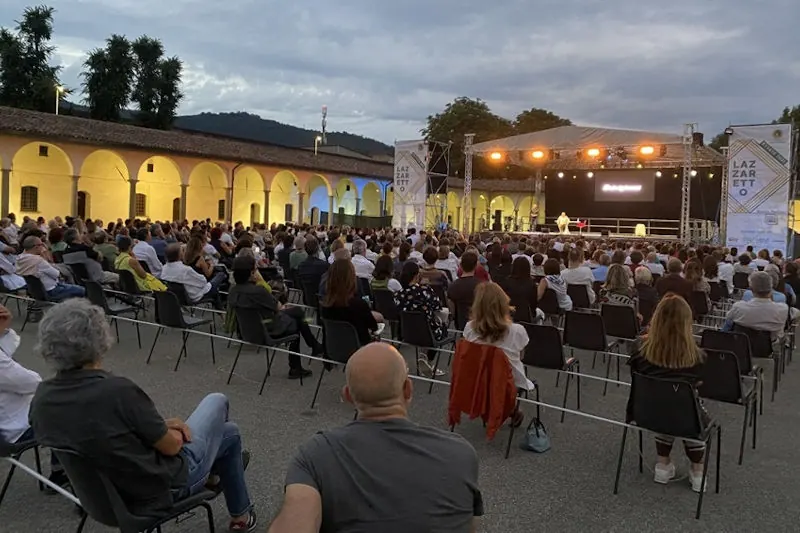 An audience seated for an evening concert in the courtyard