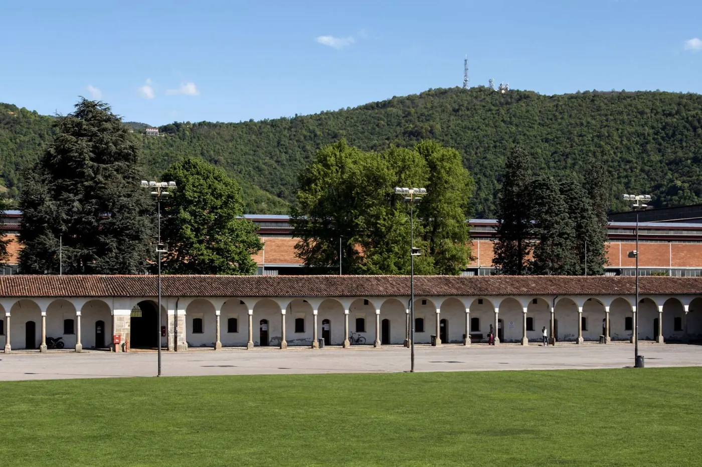 The long arcade of the Lazzaretto in Bergamo, with a lawn and wooded hill behind