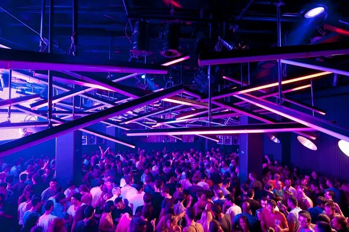 A dense dancefloor crowd under purple and blue lights