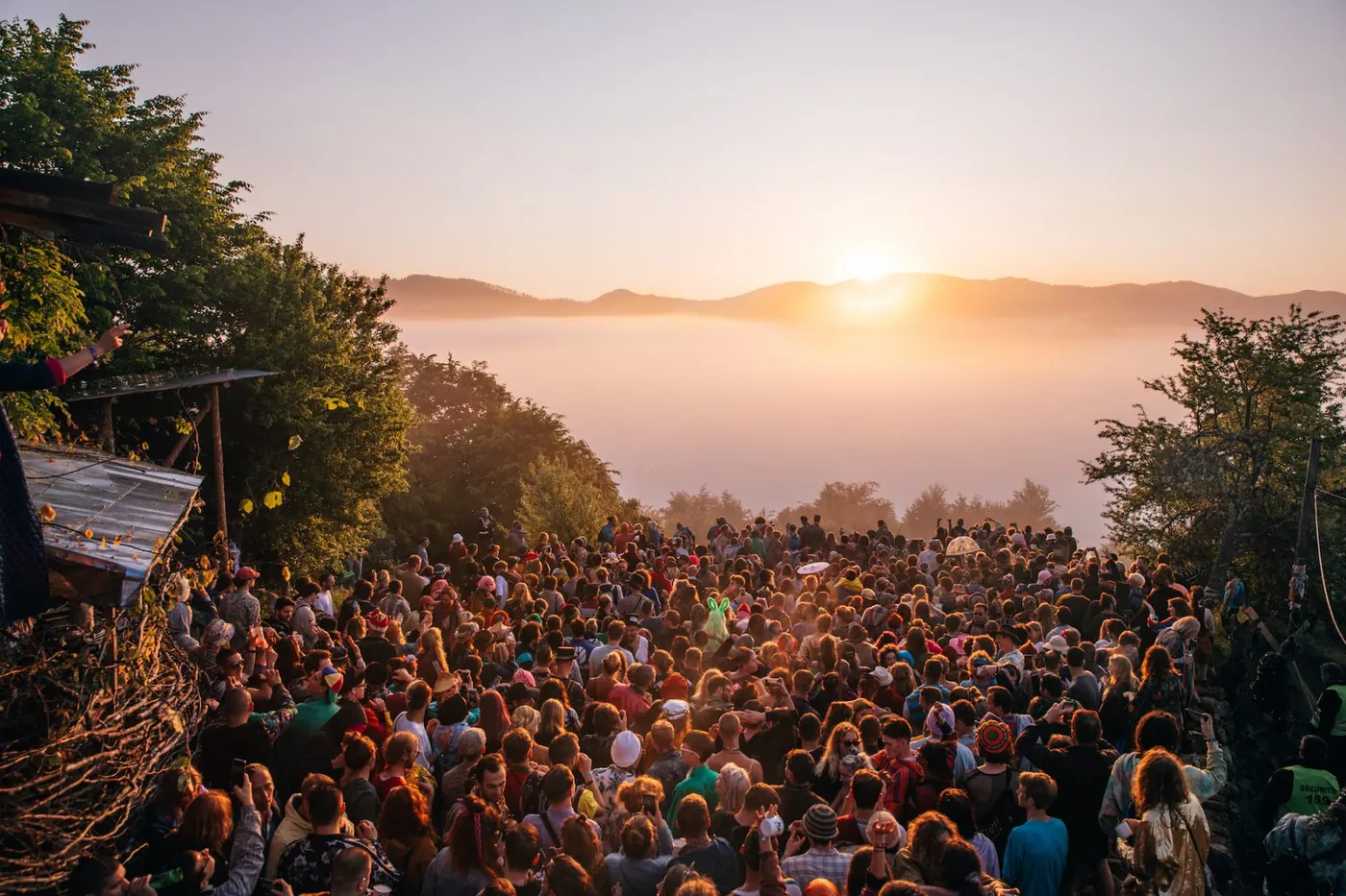 A sunlit ridge with festival-goers gathered