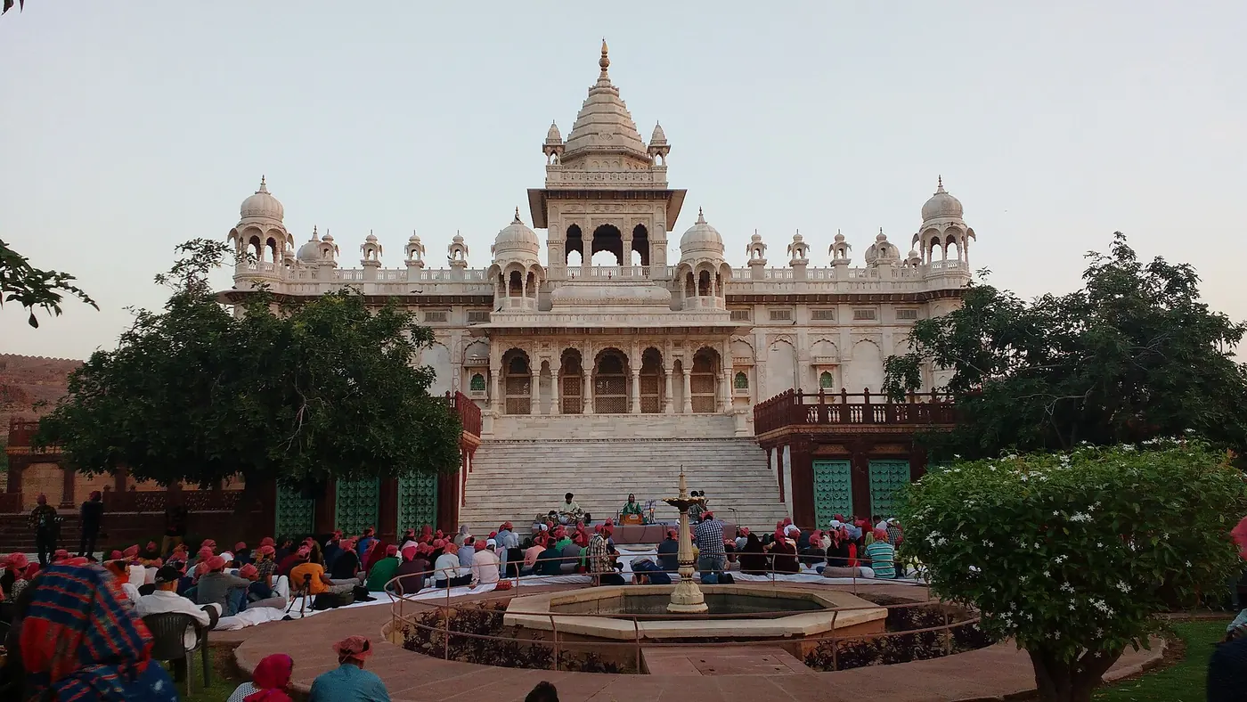 An early morning audience on the lawn before the white marble Jaswant Thada, with musicians on a small stage by the steps