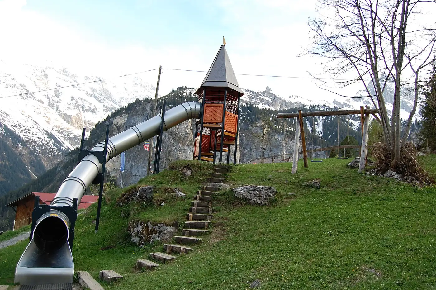 A long slide and a small tower on a grassy hillside in the Alps