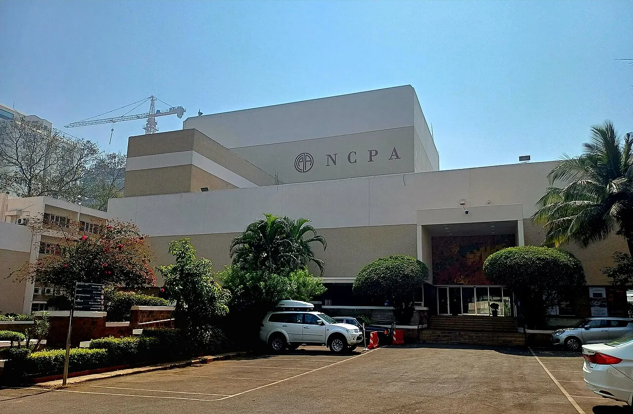 The NCPA buildings among trees, seen from the car park