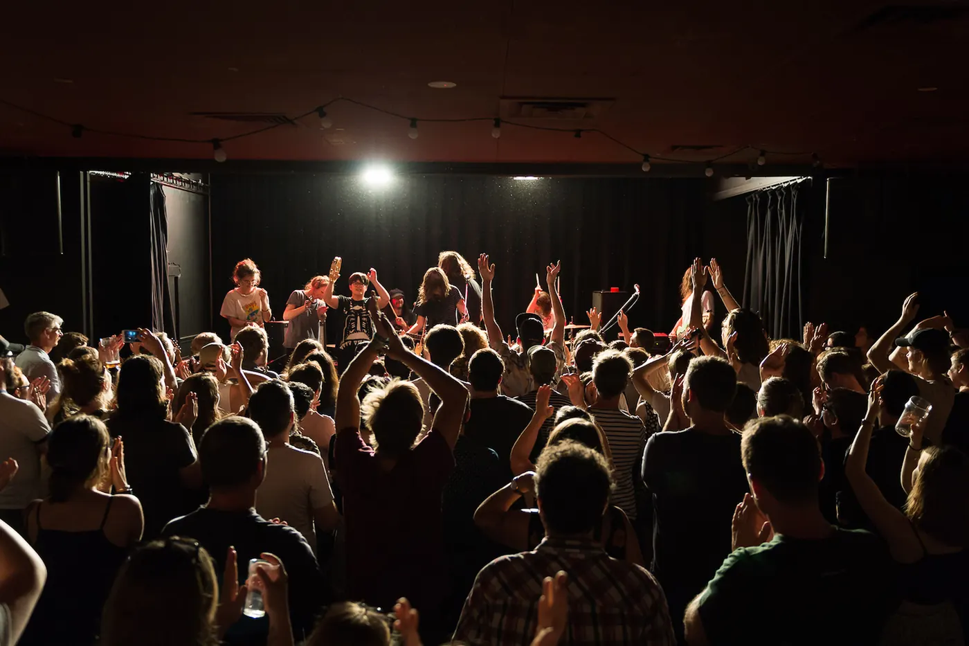 A crowd facing the stage in low light