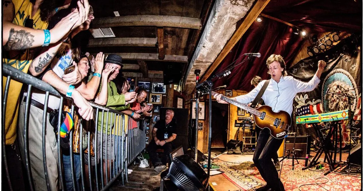 A crowd pressed against a rail in a rustic timber room