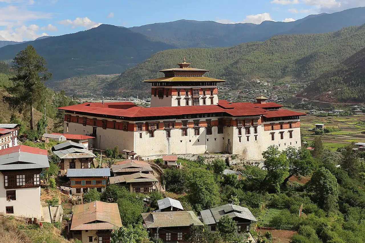 Paro's white dzong and houses on a wooded hillside