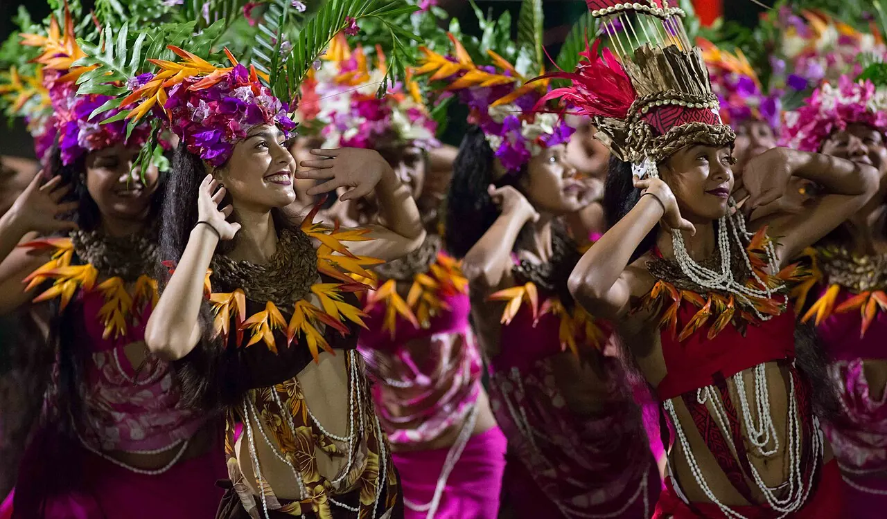 A line of dancers in purple and gold headdresses