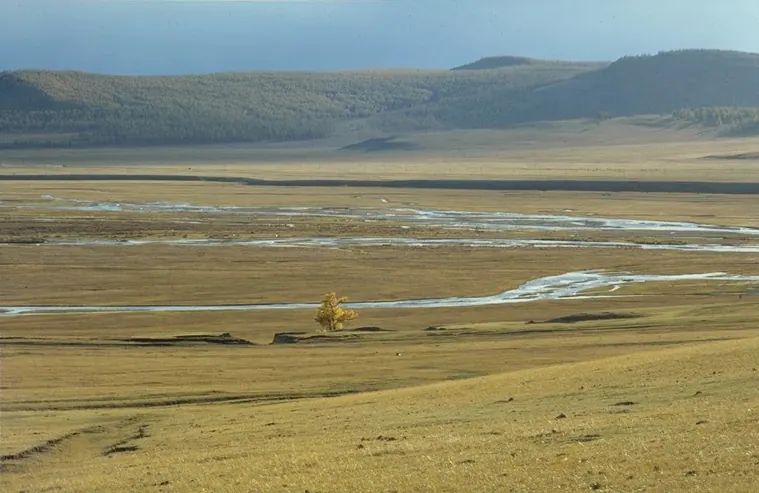 A wide dry plain crossed by a stream