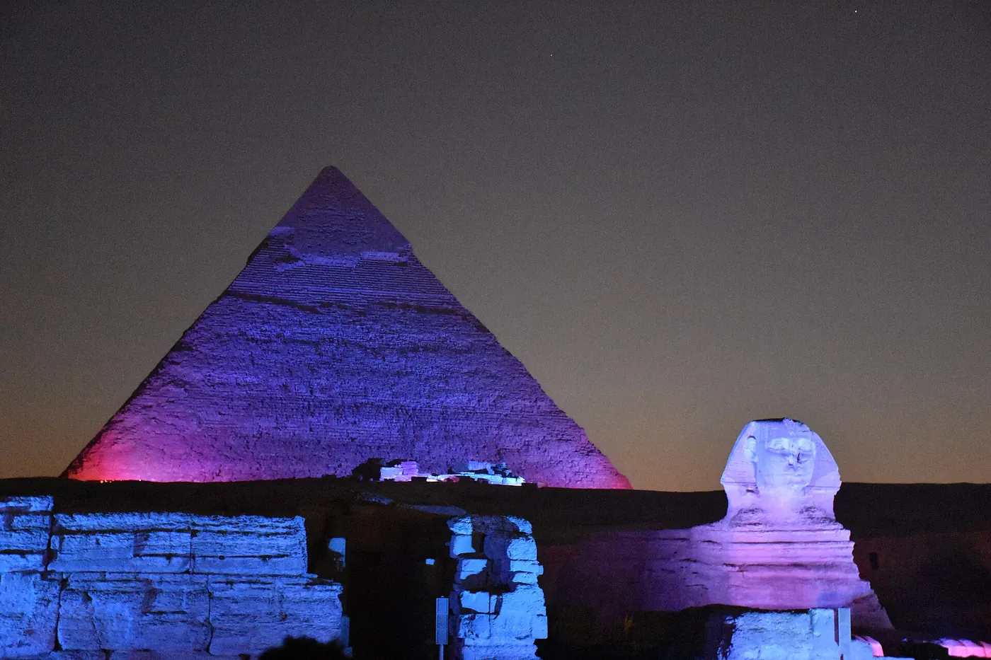 Khafre's pyramid and the Great Sphinx lit in violet, pink and blue during the Sound and Light show at Giza at dusk