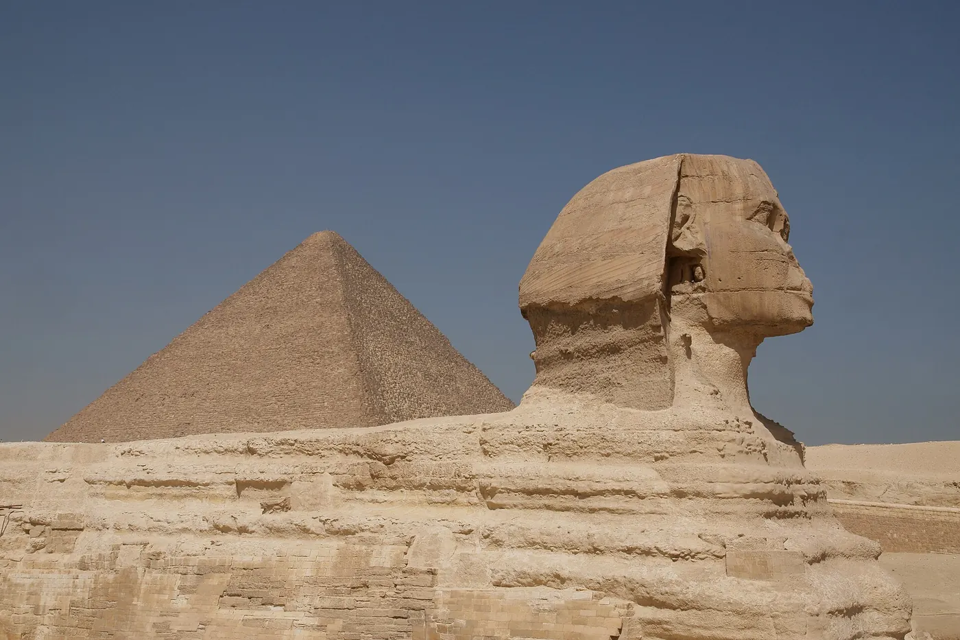 The Great Sphinx in profile with the Great Pyramid rising behind it in bright daylight on the Giza plateau