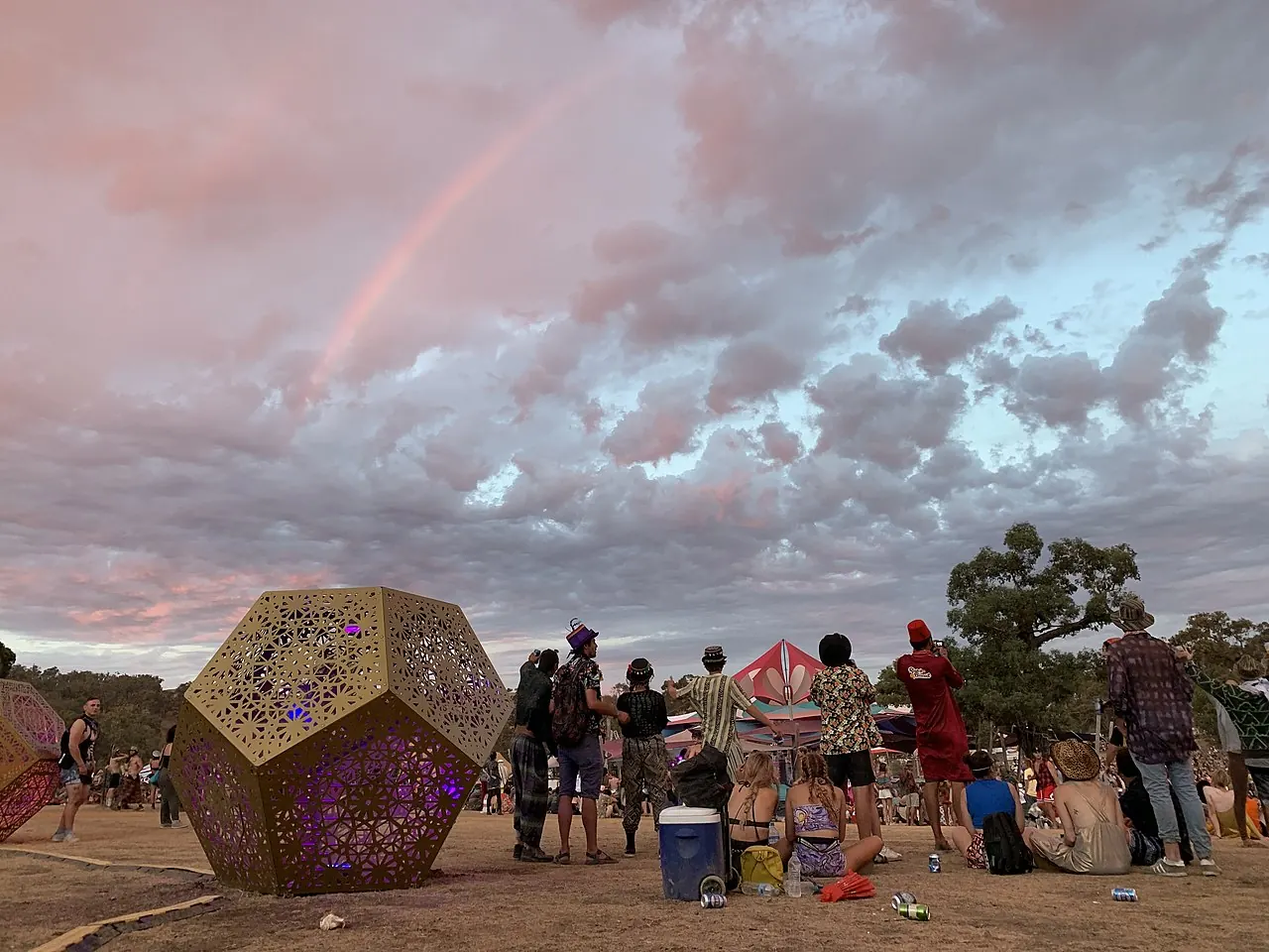 A geometric wooden structure under a pink evening sky