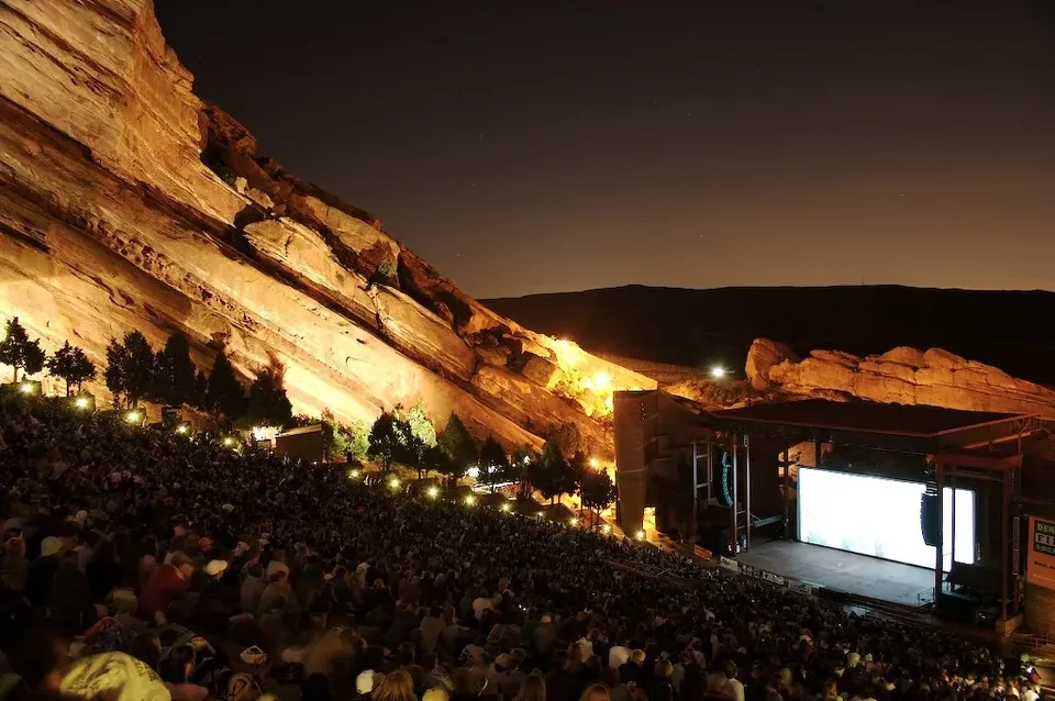 A crowd on the tiers at night facing the stage screen