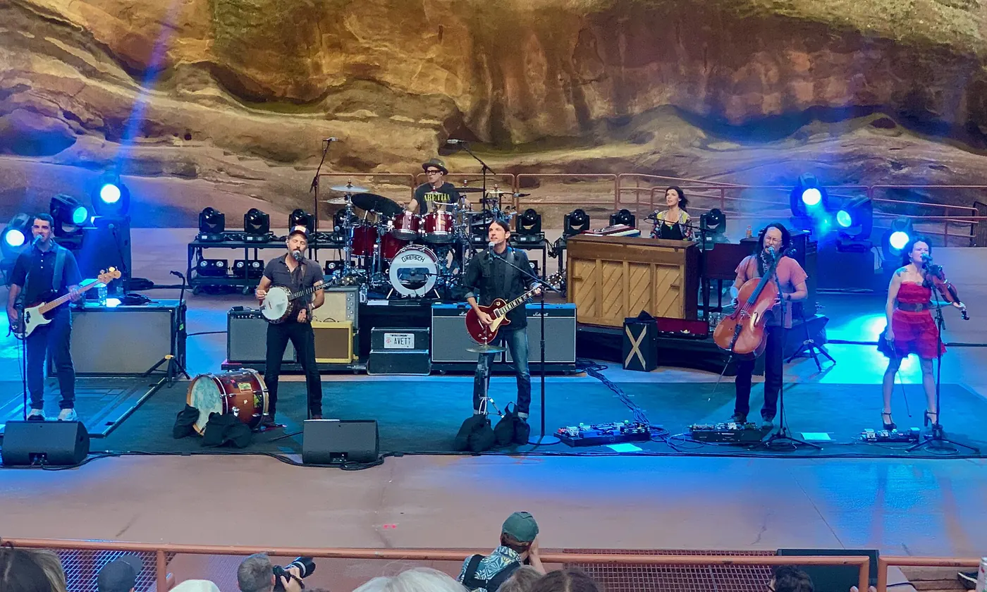 A band performing on stage at Red Rocks under blue lights