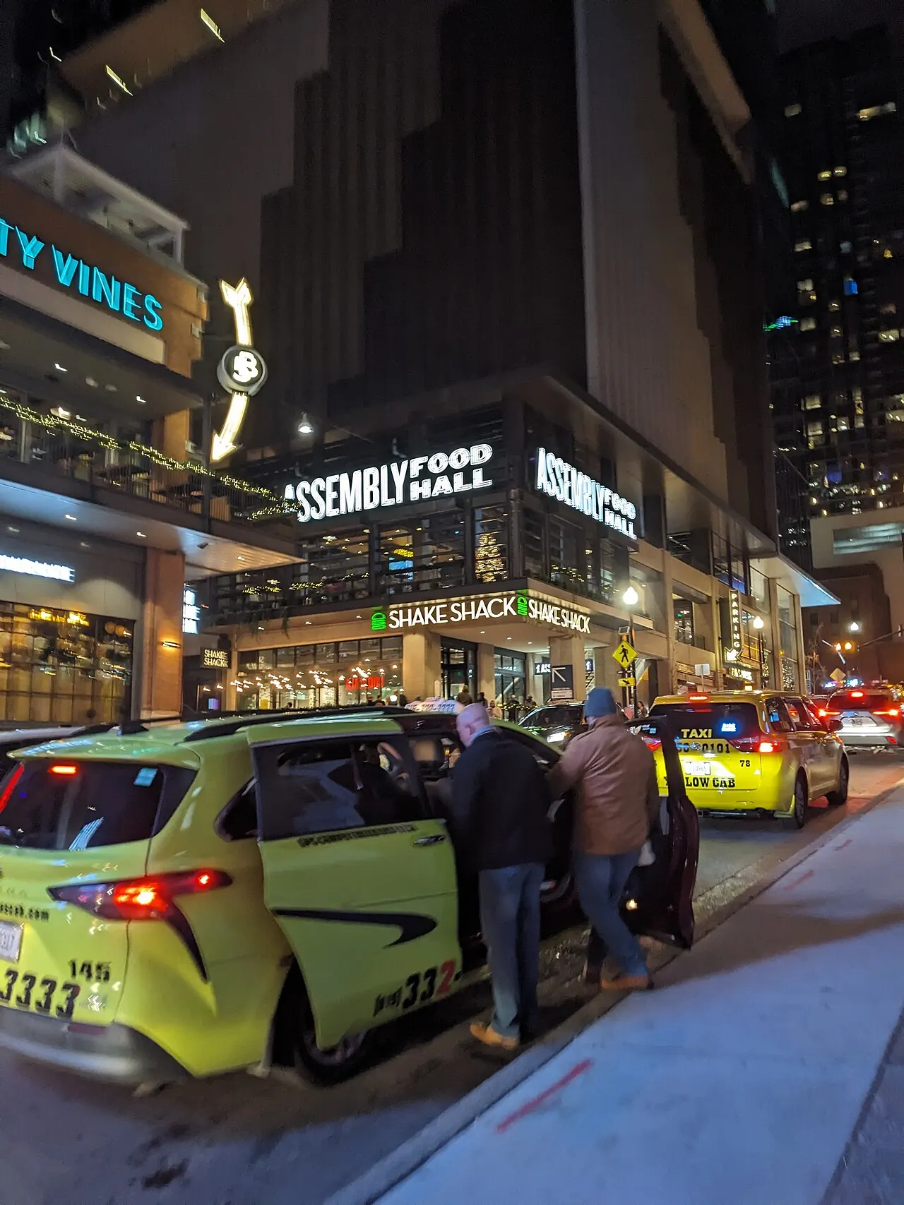 A street corner at night with a taxi outside