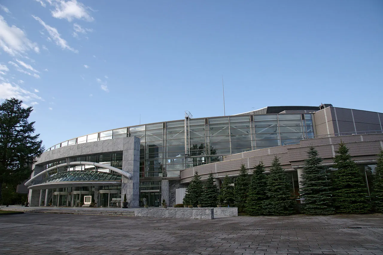 The curved roofline of the hall behind pine trees