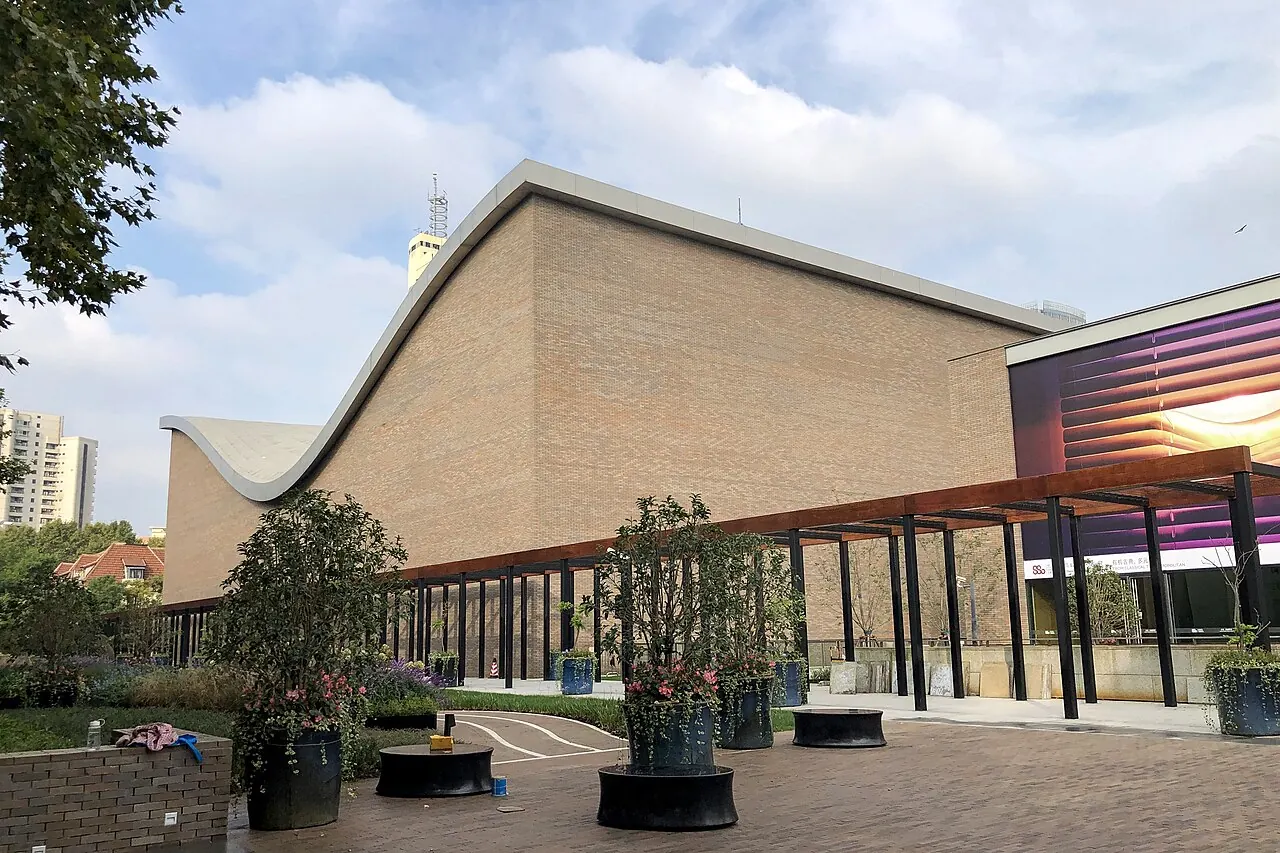 A copper-toned exterior with a curved roof and trees